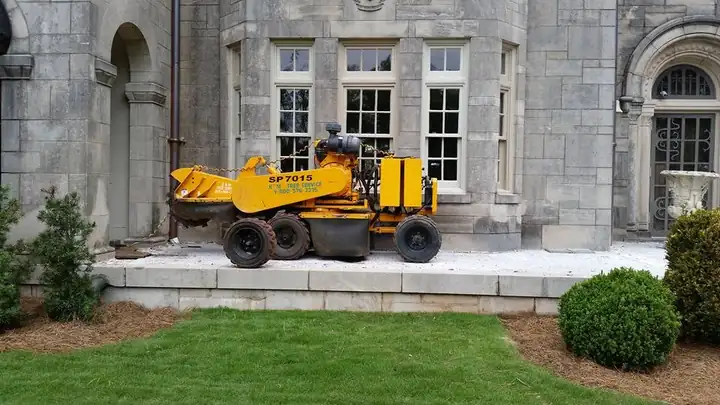 Stump grinder set up beside a stone house